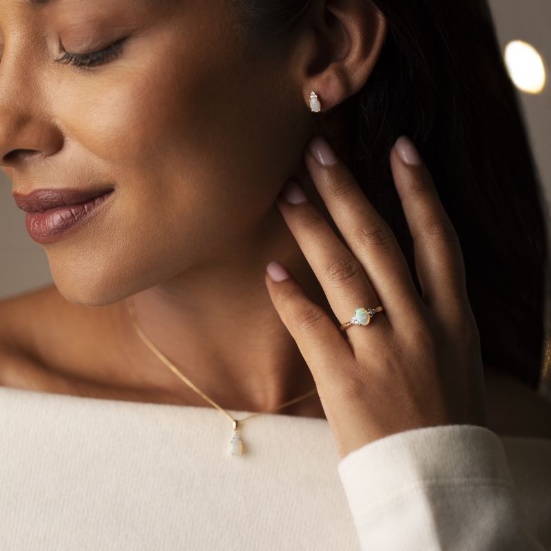 18ct yellow gold opal and diamond ring, pendant and stud earrings worn by a model, featuring oval opals with round brilliant cut diamond details.